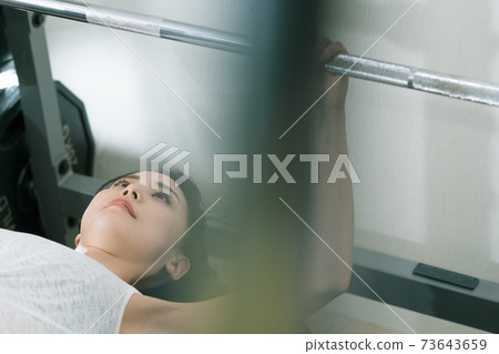 A woman doing muscle training at a gym A woman doing muscle training at a gym 73643659
