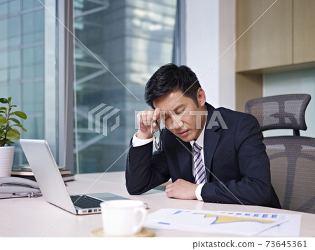 asian businessman woking in office looking tired or frustrated asian businessman woking in office looking tired or frustrated 73645361