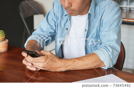 Young Asian Casual Businessman Chat Online with Customer by Using Smartphone 73645492