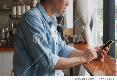 Right View Young Asian Casual Businessman Using Smartphone in Coffee Shop Right View Young Asian Casual Businessman Using Smartphone in Coffee Shop 73645493