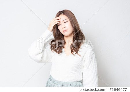 一個健康狀況不佳的年輕女子站在白牆前 一個健康狀況不佳的年輕女子站在白牆前 73646477