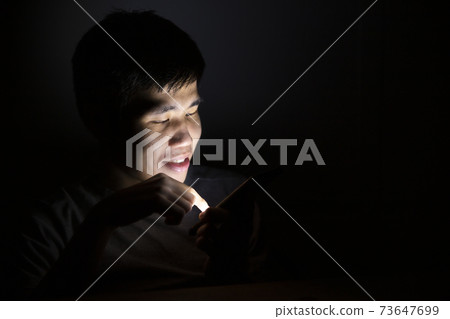 Asian man using smart phone at night. Asian man using smart phone at night. 73647699