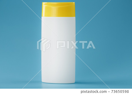 A white shampoo and shower gel bottle with a yellow lid. 73650598
