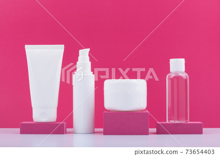 Set of cosmetic products on pink podiums against bright pink background. Concept of beauty routine and skincare Set of cosmetic products on pink podiums against bright pink background. Concept of beauty routine and skincare 73654403