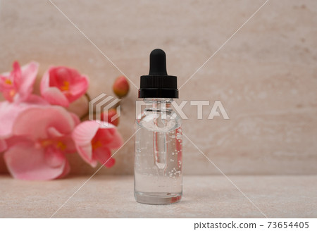 Selective focus, liquid gel or skin serum for daily or anti aging treatment against marble background with flowers Selective focus, liquid gel or skin serum for daily or anti aging treatment against marble background with flowers 73654405