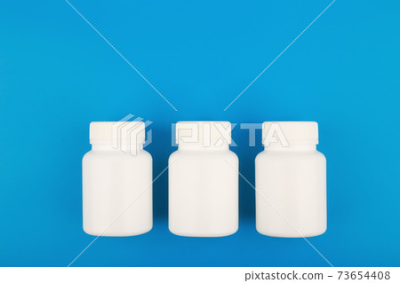 Flat lay with three white medication bottles in a row on blue background with copy space Flat lay with three white medication bottles in a row on blue background with copy space 73654408