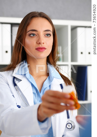 Beautiful female doctor hold in arms pill bottle 73654920