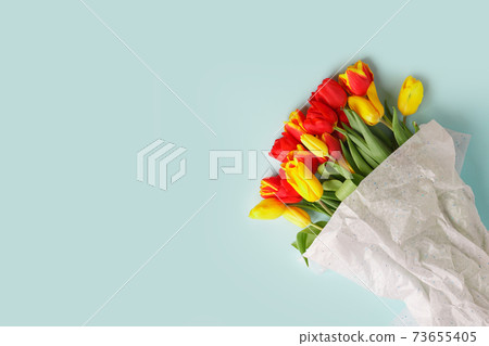 Traditional Romantic background with bouquet of red yellow tulips on blue. Top view with copy space, banner, flyer, invitation. Mother's Day, 8 March, Happy Easter background Traditional Romantic background with bouquet of red yellow tulips on blue. Top view with copy space, banner, flyer, invitation. Mother's Day, 8 March, Happy Easter background 73655405