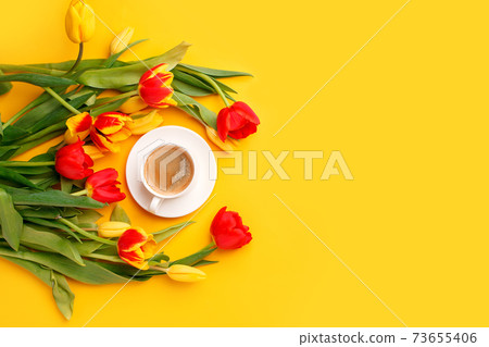 Beautiful spring breakfast on Mothers or Womans International day 8 march. Bouquet of red yellow tulips and coffee cup on bright yellow table top view. Flat lay, banner for site, seasonal flyer Beautiful spring breakfast on Mothers or Womans International day 8 march. Bouquet of red yellow tulips and coffee cup on bright yellow table top view. Flat lay, banner for site, seasonal flyer 73655406