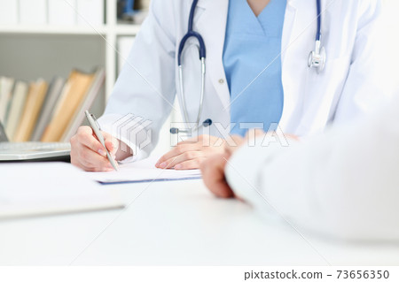 Female doctor hand hold silver pen filling patient list 73656350
