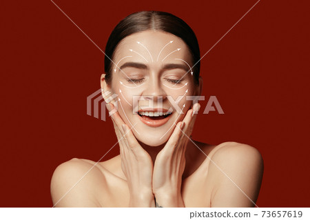Beautiful female face with lifting up arrows isolated on red background Beautiful female face with lifting up arrows isolated on red background 73657619