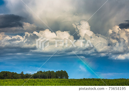 Storm clouds with rainbow part and sunrays Storm clouds with rainbow part and sunrays 73658195