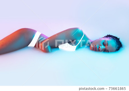 Beautiful female body in the milk bath with soft glowing in blue-pink neon light Beautiful female body in the milk bath with soft glowing in blue-pink neon light 73661865