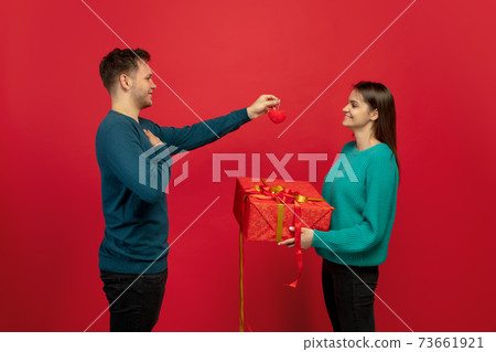 Beautiful couple in love on red studio background. Valentine's Day, love and emotions concept Beautiful couple in love on red studio background. Valentine's Day, love and emotions concept 73661921