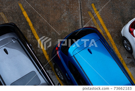 Top view of car parked at concrete car parking lot with yellow line of traffic sign on the street. Above view of car in a row at parking space. No available parking slot. Outside car parking area. 73662183