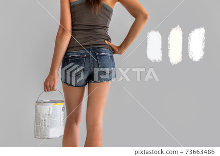 Home renovation woman confused between different shades of white paint choosing tones of warm and cold whites in eggshell sheen. Girl painting walls during house remodel Home renovation woman confused between different shades of white paint choosing tones of warm and cold whites in eggshell sheen. Girl painting walls during house remodel 73663486