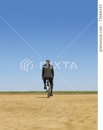Businessman Riding Bicycle In Desert 73666345
