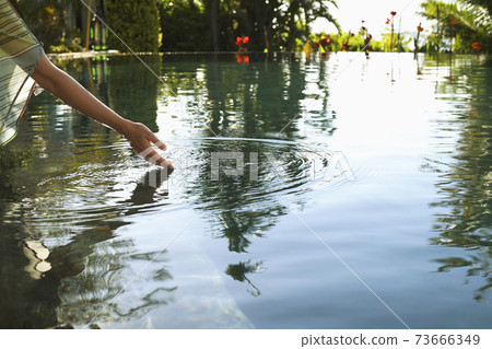 Woman Touching Water Of Swimming Pool 73666349