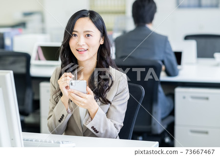 Business woman operating a smartphone in the office 73667467