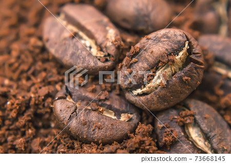 Close-up of coffee beans, freshly roasted coffee grains lie on a heap of ground coffee Close-up of coffee beans, freshly roasted coffee grains lie on a heap of ground coffee 73668145