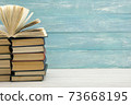 Composition with vintage old hardback books, diary, fanned pages on wooden deck table and red background. Books stacking. Back to school. Copy Space. Education background. 73668195