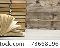 Composition with vintage old hardback books, diary, fanned pages on wooden deck table and red background. Books stacking. Back to school. Copy Space. Education background. 73668196