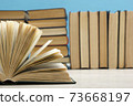 Composition with vintage old hardback books, diary, fanned pages on wooden deck table and red background. Books stacking. Back to school. Copy Space. Education background. 73668197