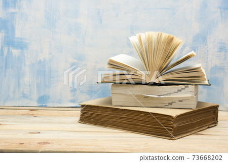 Composition with vintage old hardback books, diary, fanned pages on wooden deck table and red background. Books stacking. Back to school. Copy Space. Education background. 73668202