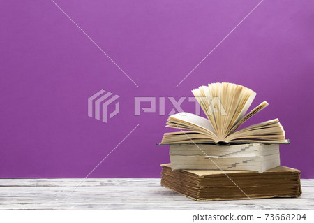 Composition with vintage old hardback books, diary, fanned pages on wooden deck table and red background. Books stacking. Back to school. Copy Space. Education background. 73668204
