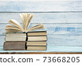 Composition with vintage old hardback books, diary, fanned pages on wooden deck table and red background. Books stacking. Back to school. Copy Space. Education background. 73668205