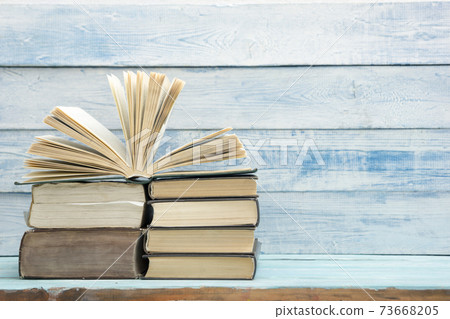 Composition with vintage old hardback books, diary, fanned pages on wooden deck table and red background. Books stacking. Back to school. Copy Space. Education background. 73668205