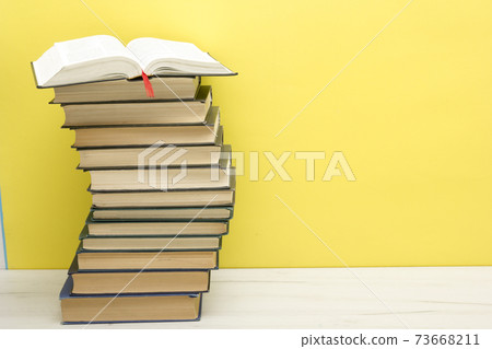 Composition with vintage old hardback books, diary, fanned pages on wooden deck table and red background. Books stacking. Back to school. Copy Space. Education background. 73668211
