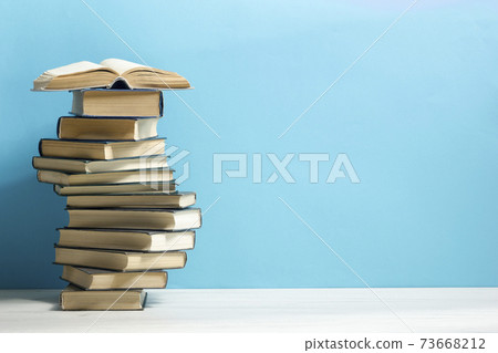 Composition with vintage old hardback books, diary, fanned pages on wooden deck table and red background. Books stacking. Back to school. Copy Space. Education background. 73668212