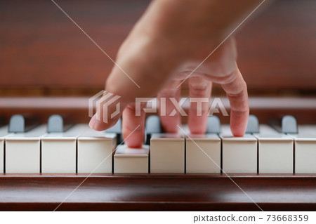 Female finger playing walnut upright piano Female finger playing walnut upright piano 73668359