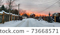 Photo of an evening street with a fence and houses in the rays of the sunset 73668571