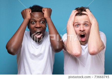 African and caucasian men feel scared afraid and shocked by unexpected news. 73668745