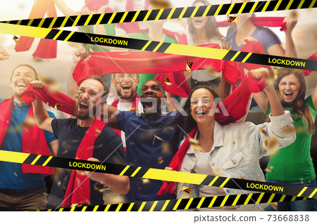 Female and male soccer fans cheering for favourite sport team with bright emotions, excited, wondered behind the limiting tapes with Lockdown Female and male soccer fans cheering for favourite sport team with bright emotions, excited, wondered behind the limiting tapes with Lockdown 73668838