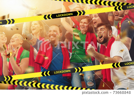 Female and male soccer fans cheering for favourite sport team with bright emotions, excited, wondered behind the limiting tapes with Lockdown Female and male soccer fans cheering for favourite sport team with bright emotions, excited, wondered behind the limiting tapes with Lockdown 73668848