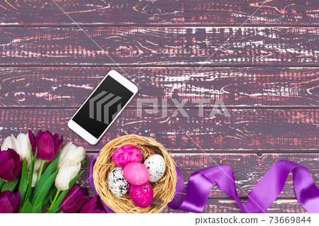 easter, holidays, tradition and object concept - close up of colored easter eggs, tulip flowers and smartphone easter, holidays, tradition and object concept - close up of colored easter eggs, tulip flowers and smartphone 73669844