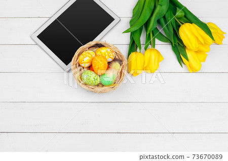 tablet screen for message and colorful tulips and easter eggs on wooden background tablet screen for message and colorful tulips and easter eggs on wooden background 73670089