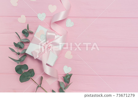 Valentines day or wedding gift, eucalyptus leaves frame paper hearts confetti and wooden pink background, empty space for your text, top view flat lay 73671279