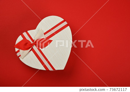 White heart shaped gift box over red White heart shaped gift box over red 73672117