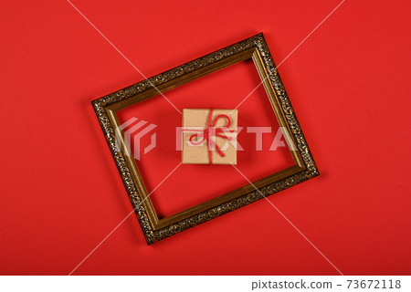 Brown paper giftbox in golden frame on red Brown paper giftbox in golden frame on red 73672118