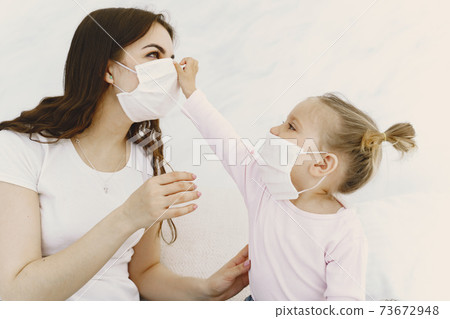 Mother and baby at home with medical masks 73672948