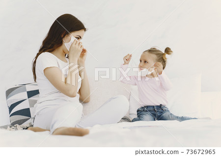 Mother and baby at home with medical masks 73672965