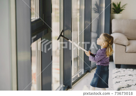 Little girl cleaning windows with vacuum cleaner Little girl cleaning windows with vacuum cleaner 73673018