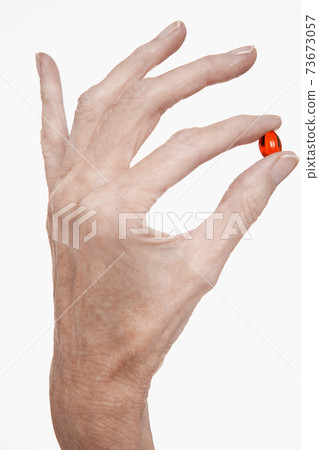 Closeup Of Finger And Thumb Holding Red Pill Closeup Of Finger And Thumb Holding Red Pill 73673057