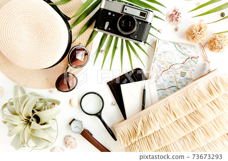 Traveler accessories on white background with retro camera, straw hat, bag, sunglasses, map and tropical palm leaf. Traveler accessories on white background with retro camera, straw hat, bag, sunglasses, map and tropical palm leaf. 73673293