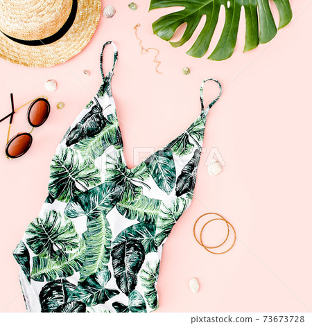 Woman's beach accessories: swimsuit with tropical print, straw hat on pink background. Summer background. Flat lay Woman's beach accessories: swimsuit with tropical print, straw hat on pink background. Summer background. Flat lay 73673728