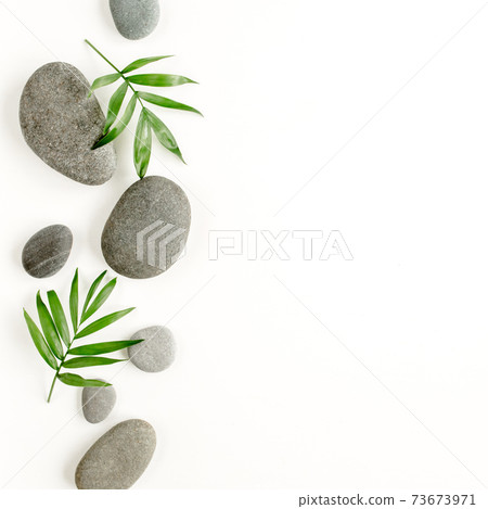 Spa stones, palm leaves, candle and zen like grey stones on white background. Flat lay, top view Spa stones, palm leaves, candle and zen like grey stones on white background. Flat lay, top view 73673971